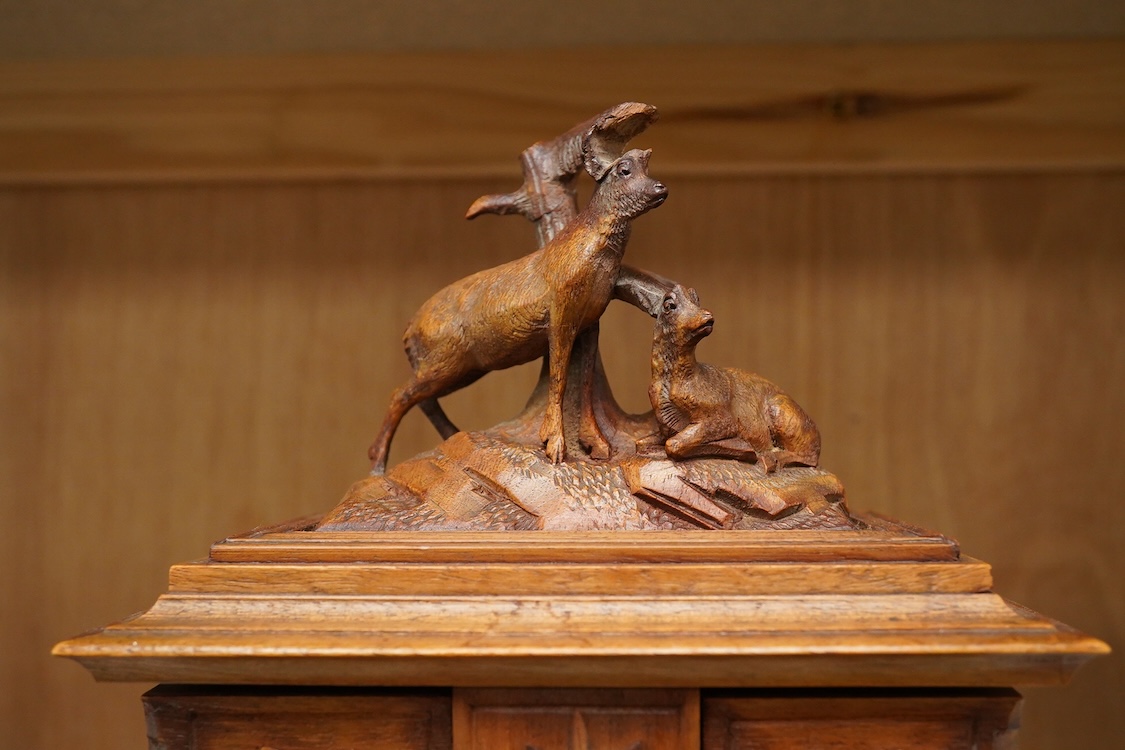 A 20th century black forest carved wood jewellery box, surmounted with two deer, 28cm high